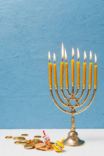 A lit menorah and gelt, two popular items used to celebrate the Jewish holiday, Hanukkah. (Freepik)