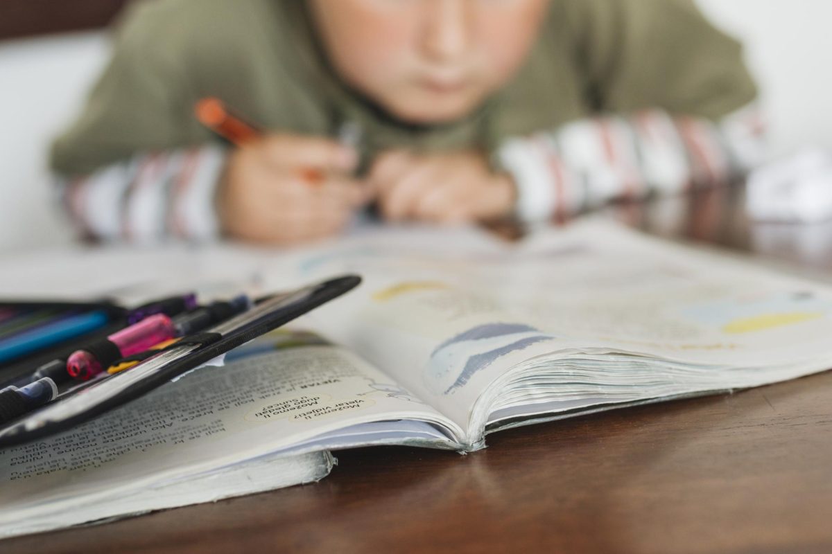 Child hunched over the table straining their eyes to look at homework. (freepik)