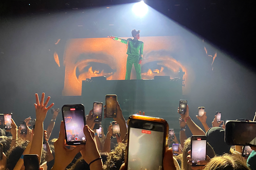 Fans raise their phones as Tyler The Creator lights up the stage.